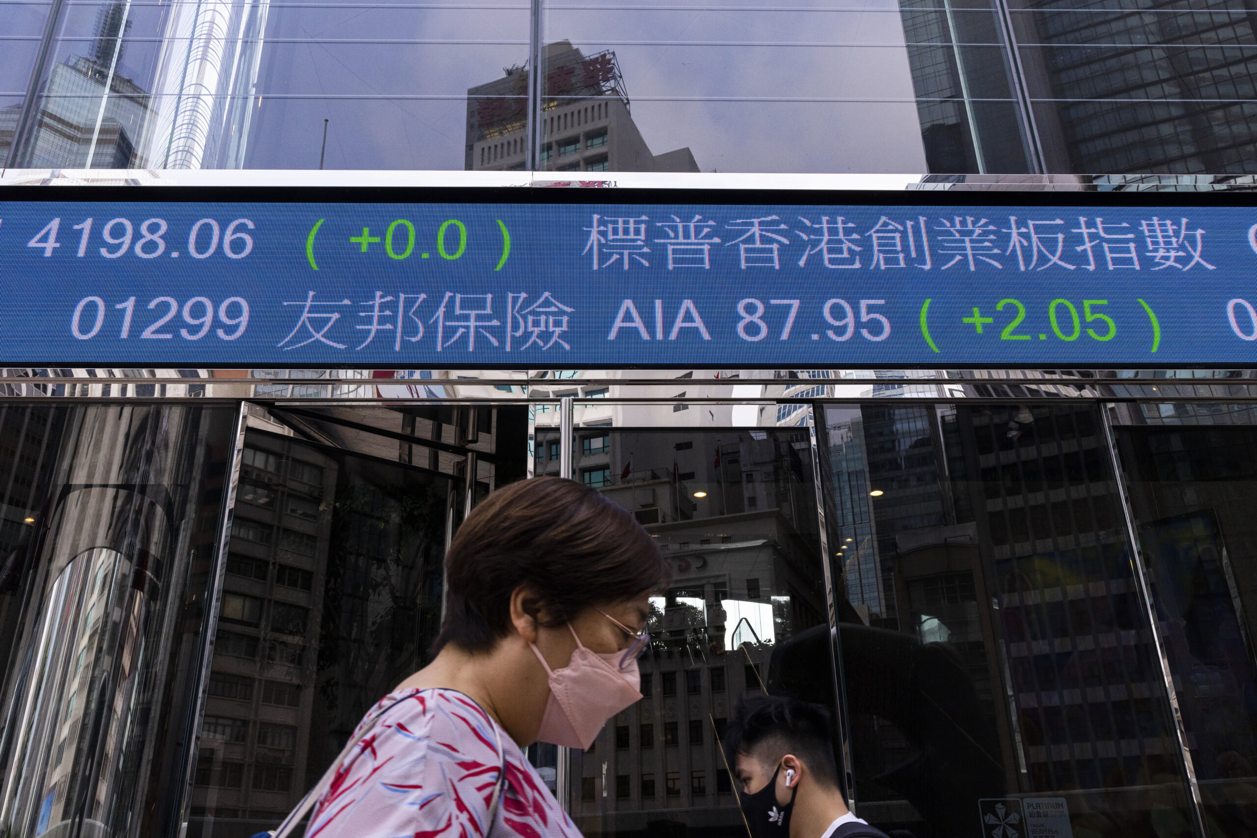 Pedestrians pass by the Hong Kong Stock Exchange electronic screen in Hong Kong, Tuesday, April 18,...