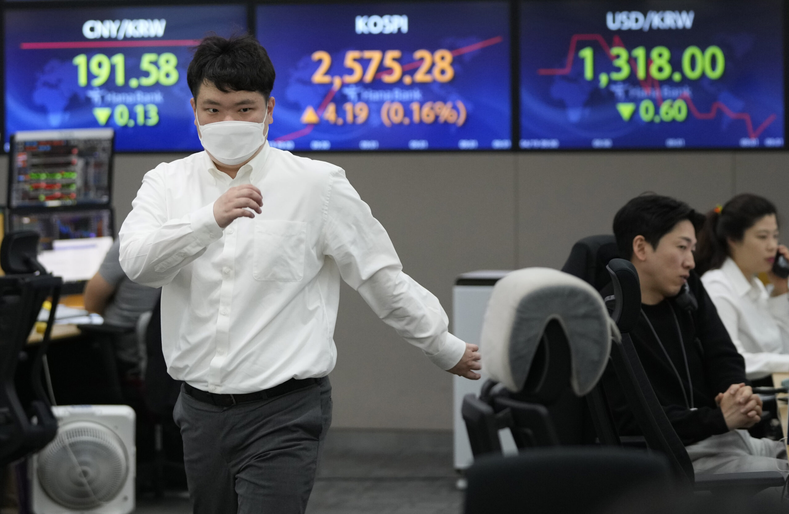 A currency trader passes by screens showing the Korea Composite Stock Price Index (KOSPI), top cent...
