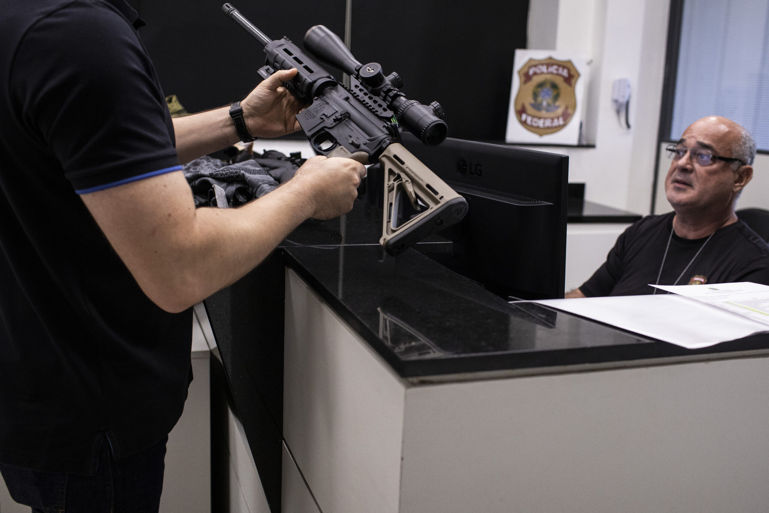 A gun owner holds a weapon as a police officer registers his firearms with the Federal Police on th...