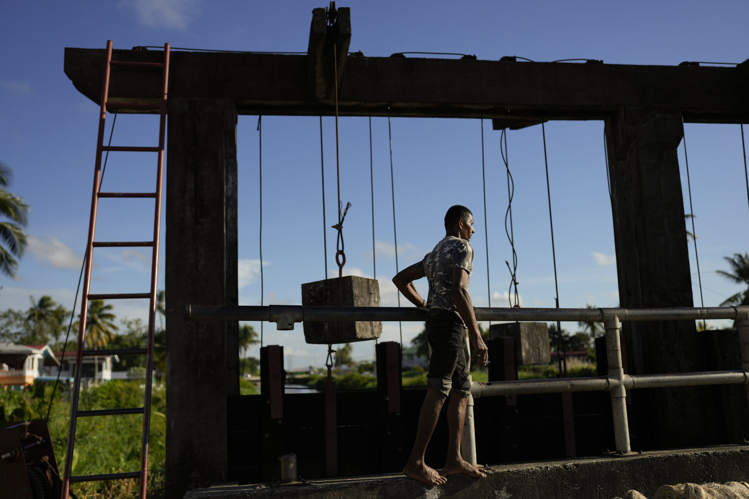 Gate operator Hakim Altaf checks the gate on the seawall in Georgetown, Guyana, Thursday, April 13,...