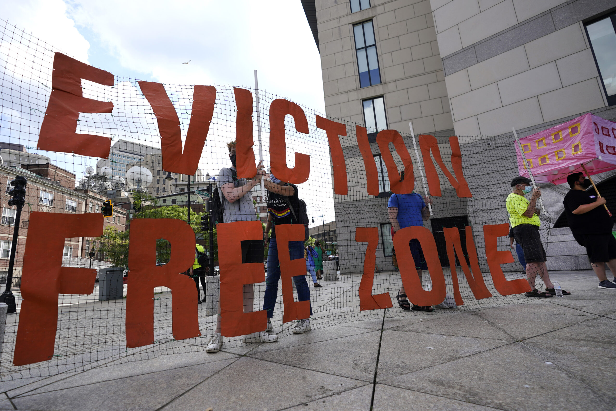 FILE - In this June 9, 2021, photo, people hold a sign during a rally in Boston protesting housing ...