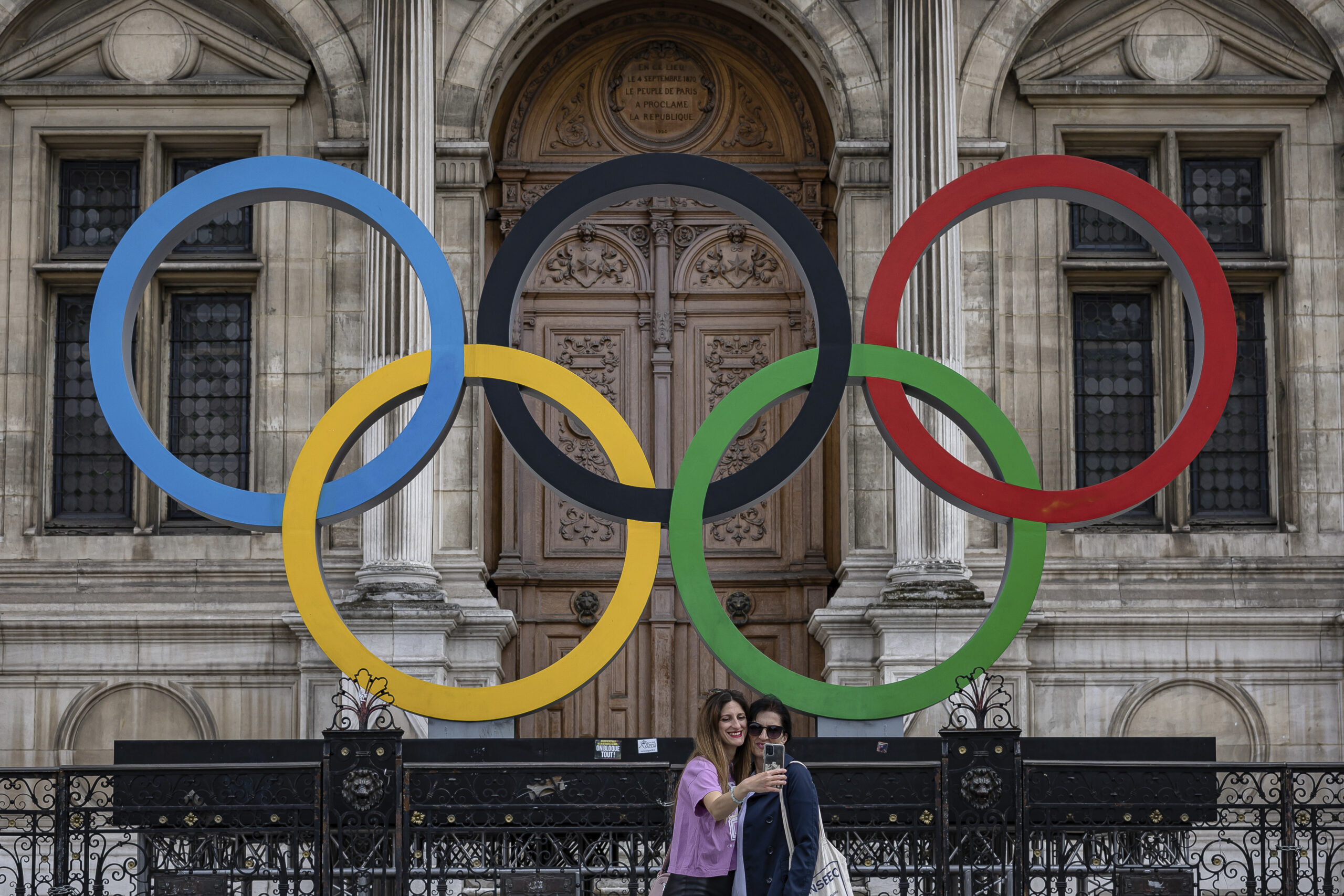 People take a photographs of the Olympic rings in front of the Paris City Hall, in Paris, Sunday, A...