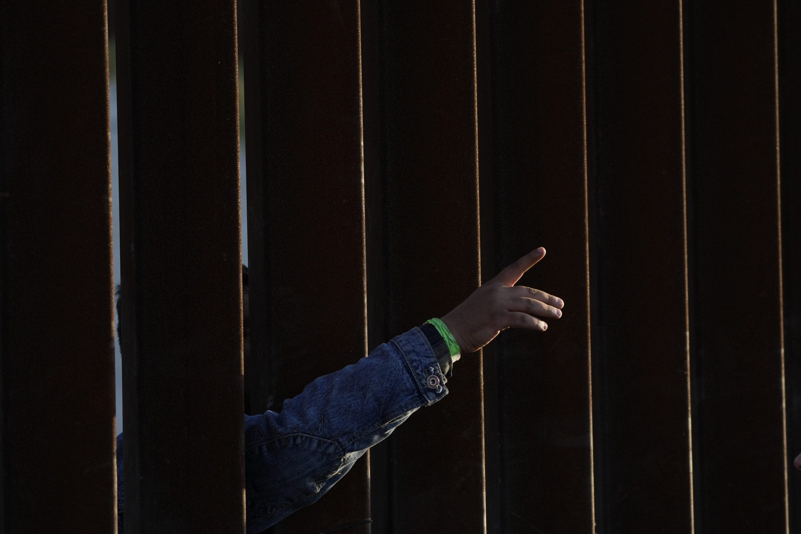 A man gestures as he waits with others to apply for asylum between two border walls Thursday, May 1...