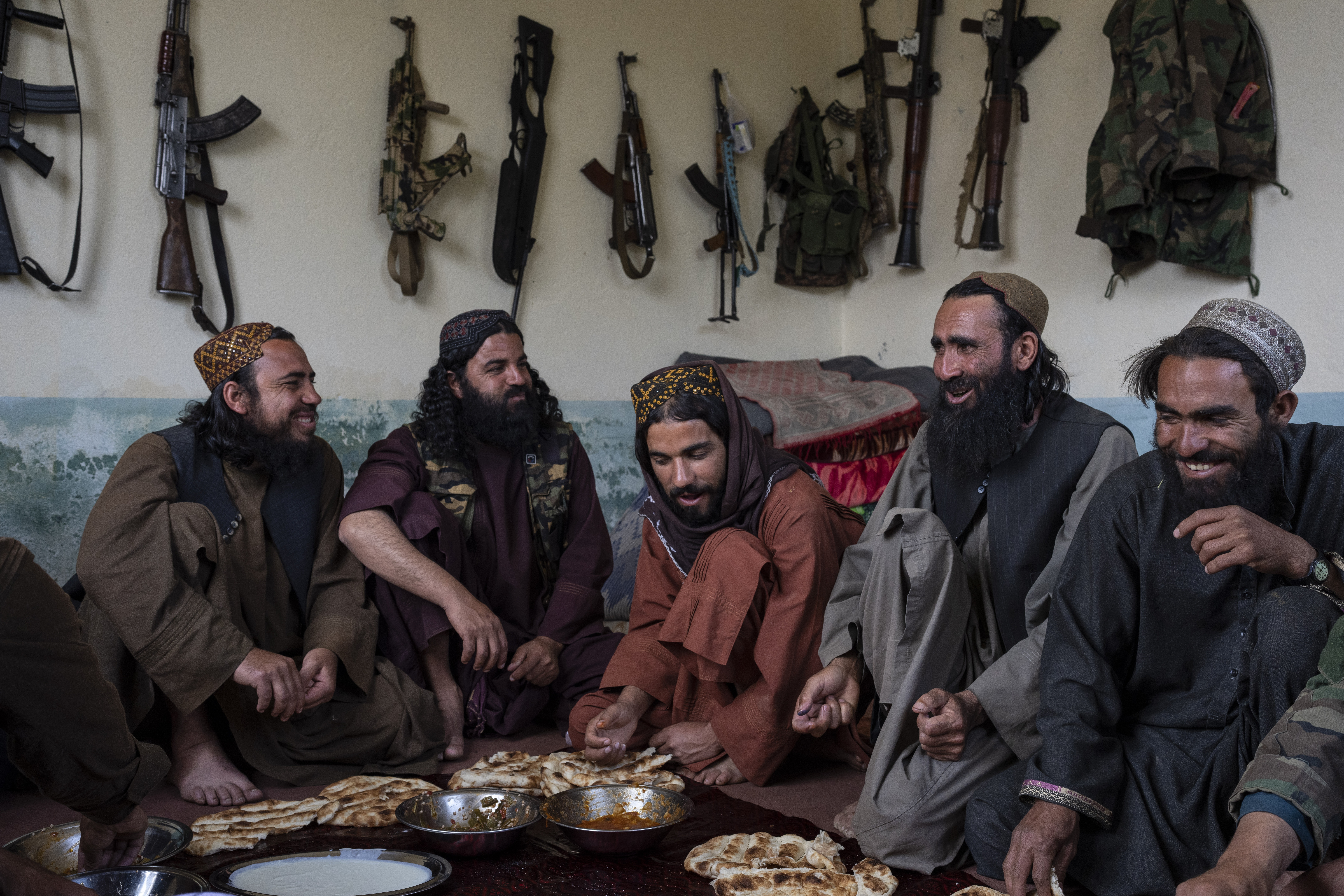 Taliban fighters enjoy lunch inside an adobe house that is used as a makeshift checkpoint in Wardak...