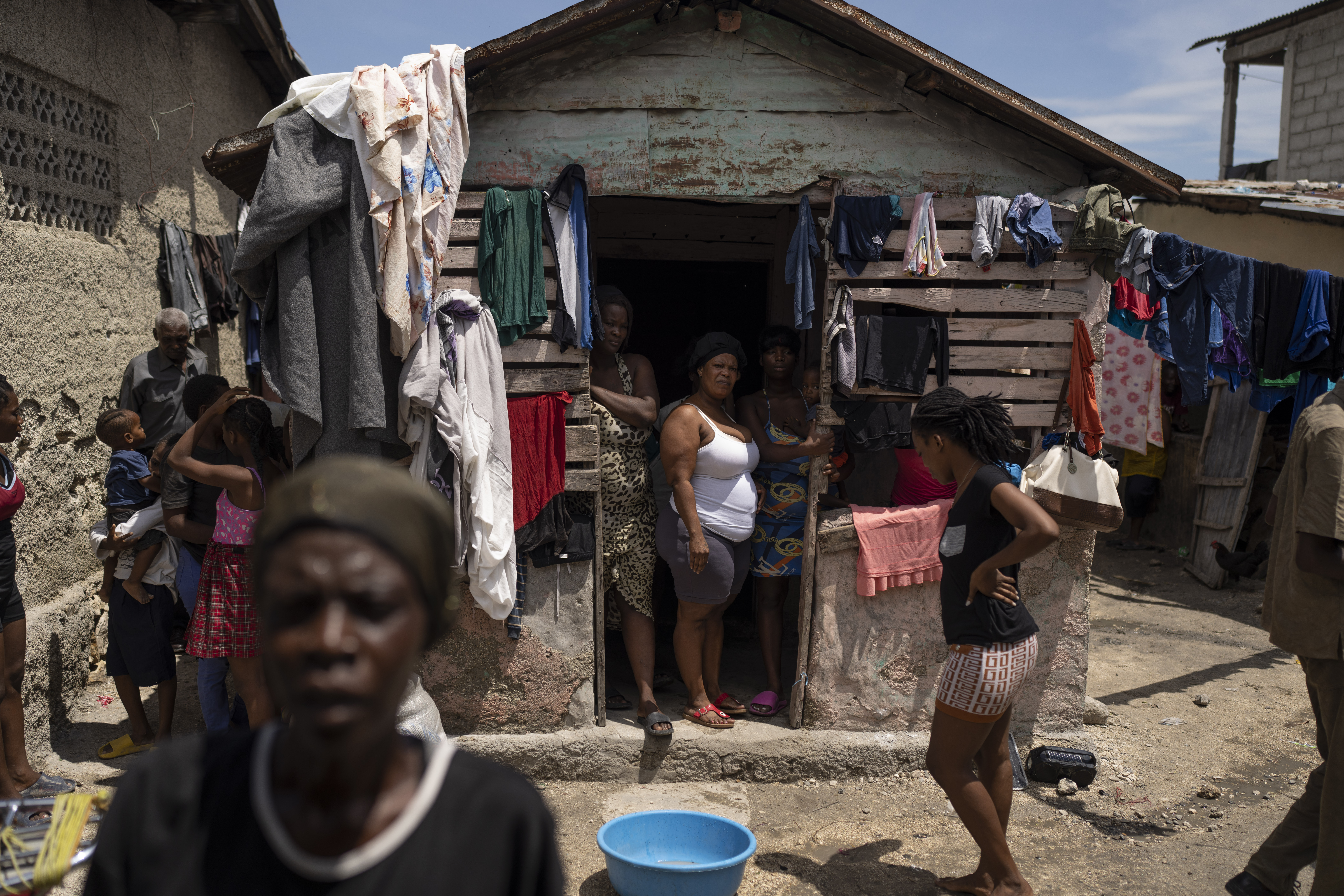 People displaced by gang violence stand in Jean-Kere Almicar's front yard, where they have sought r...