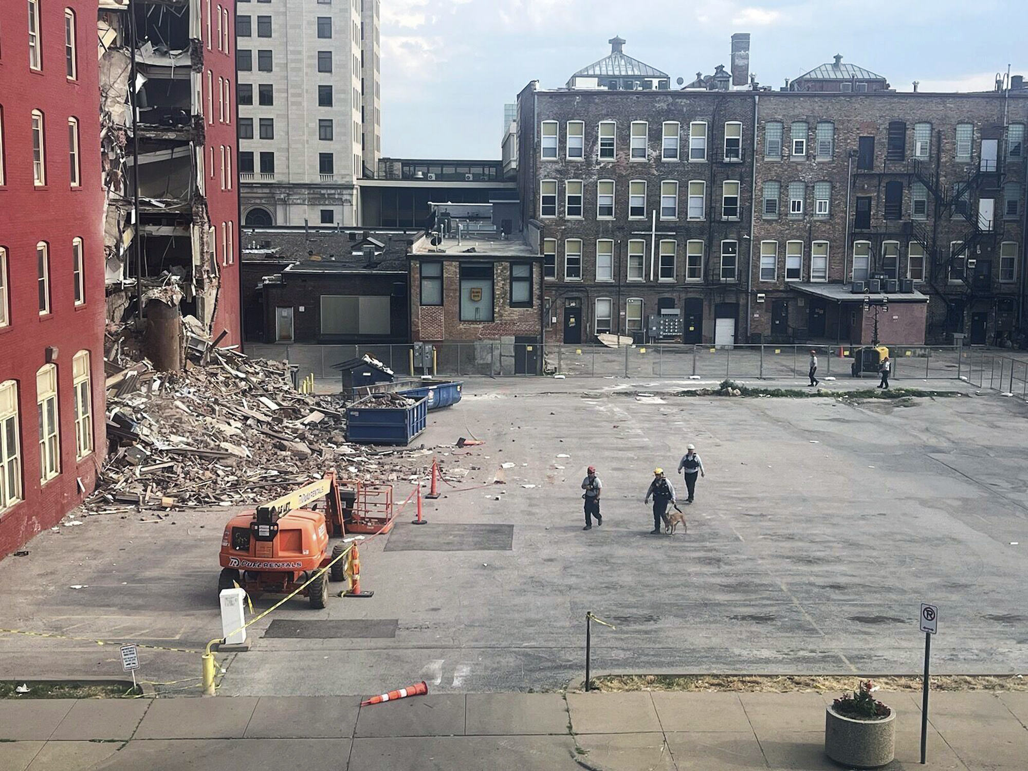 Three search and rescue workers and a dog approach the site of a building collapse in Davenport, Io...