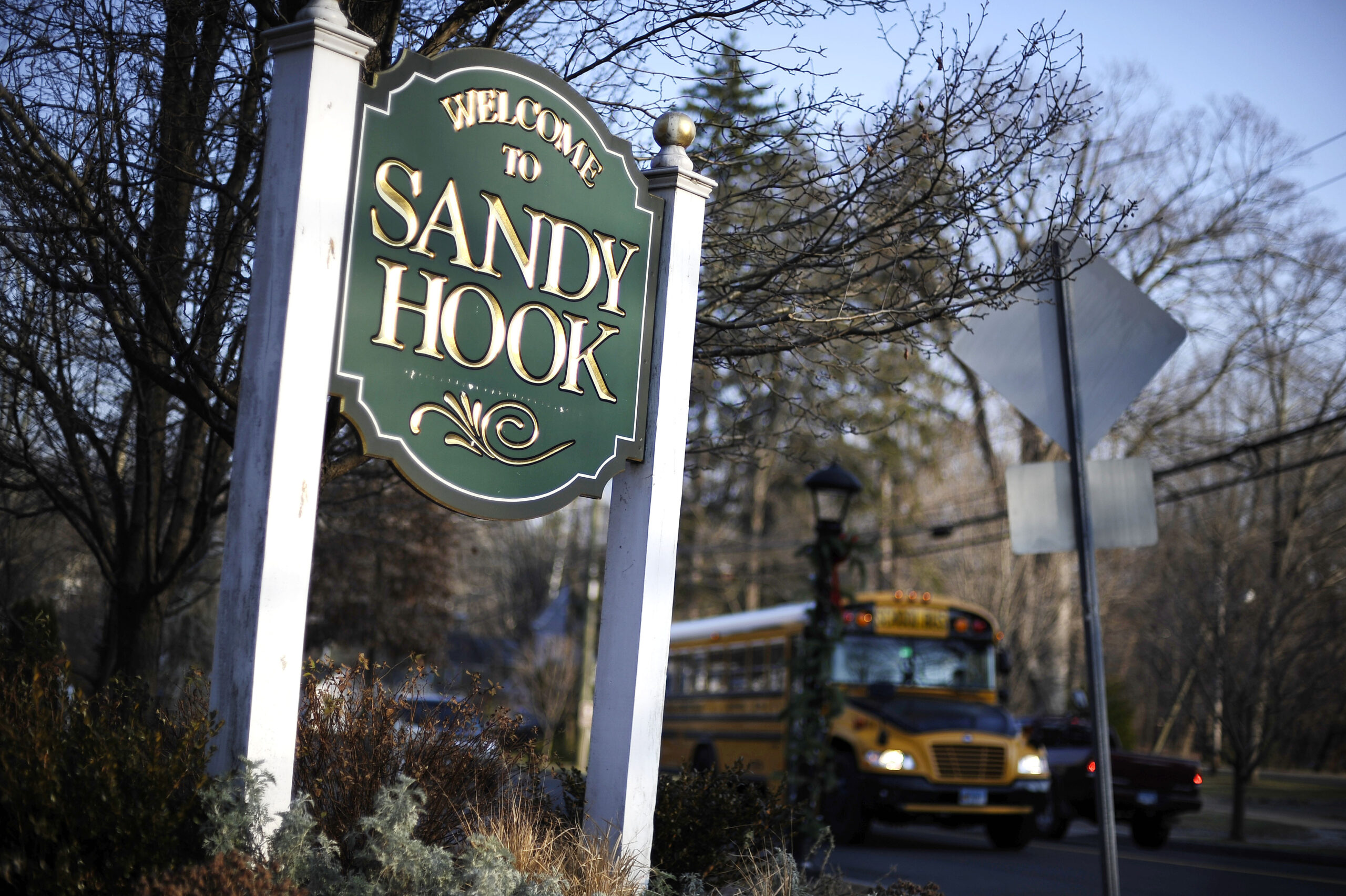 FILE - A bus drives past a sign reading Welcome to Sandy Hook in Newtown, Conn., Dec. 4, 2013. Conn...