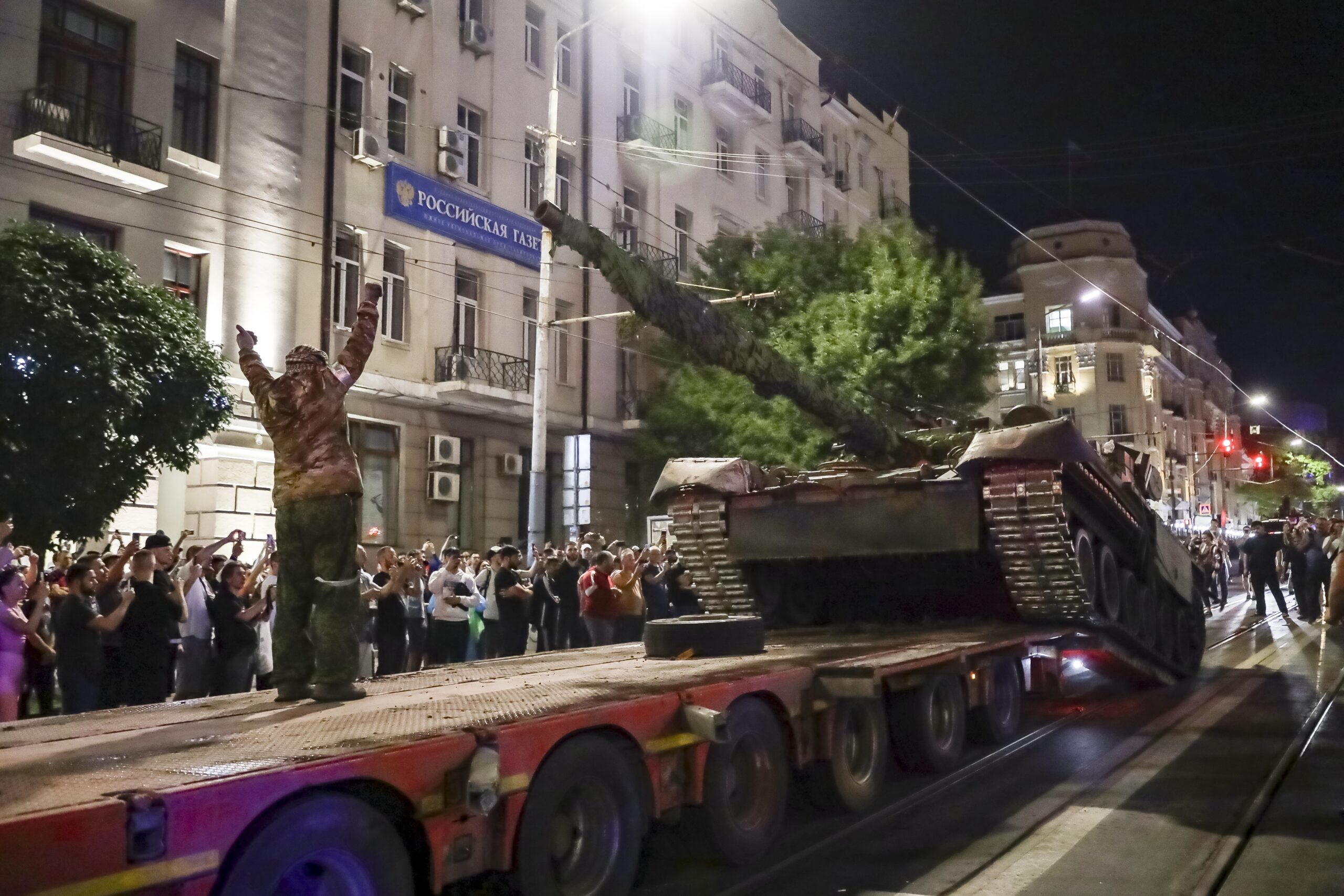 FILE - Members of the Wagner Group military company load their tank onto a truck on a street in Ros...