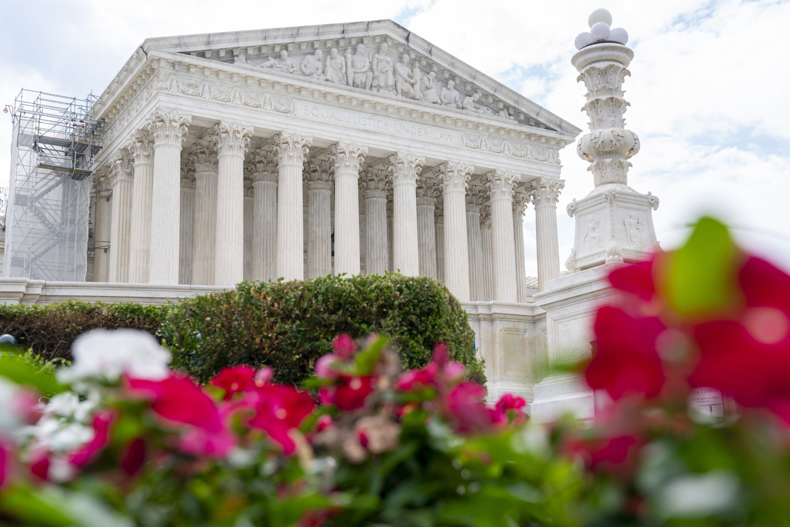 The Supreme Court is seen behind flowers, Tuesday, June 27, 2023, in Washington, as decisions are e...