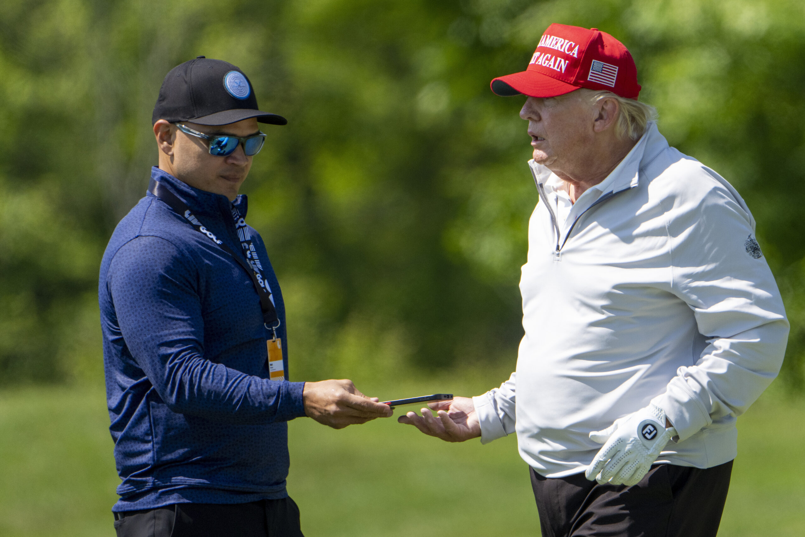 Walt Nauta, left, takes a phone from Former President Donald Trump during the LIV Golf Pro-Am at Tr...