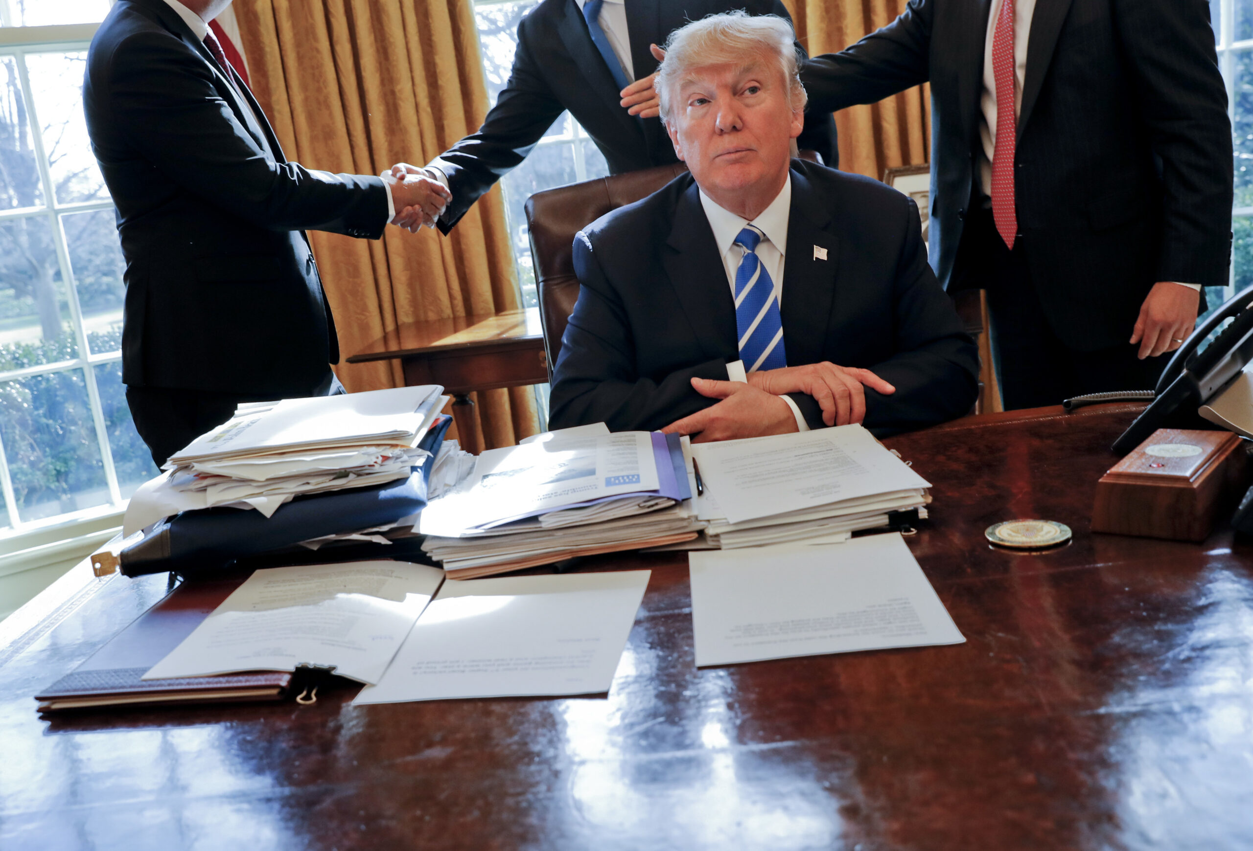 FILE - President Donald Trump sits at his desk after a meeting with Intel CEO Brian Krzanich, left,...