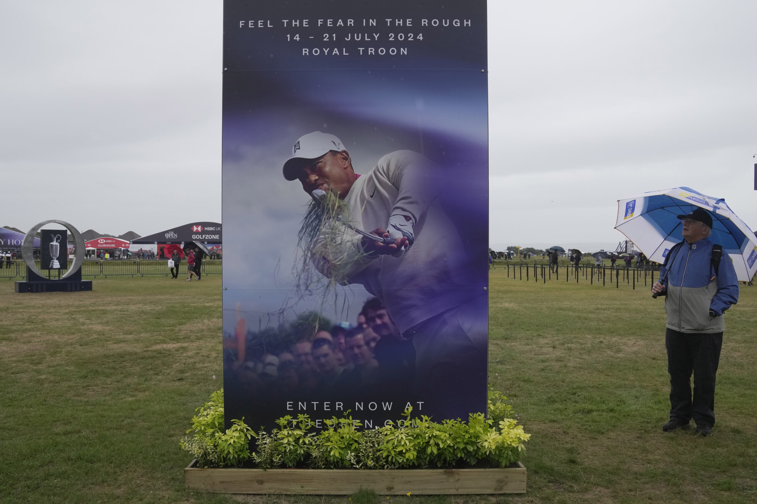 A spectator looks at a poster for the British Open 2024, featuring a picture of United States golfe...