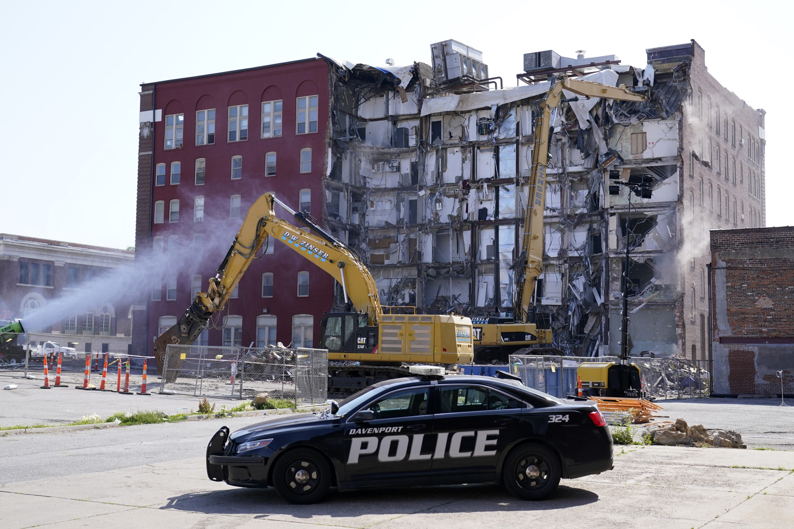 FILE - A police officer sits parked at the site of a building collapse at the start of demolition, ...