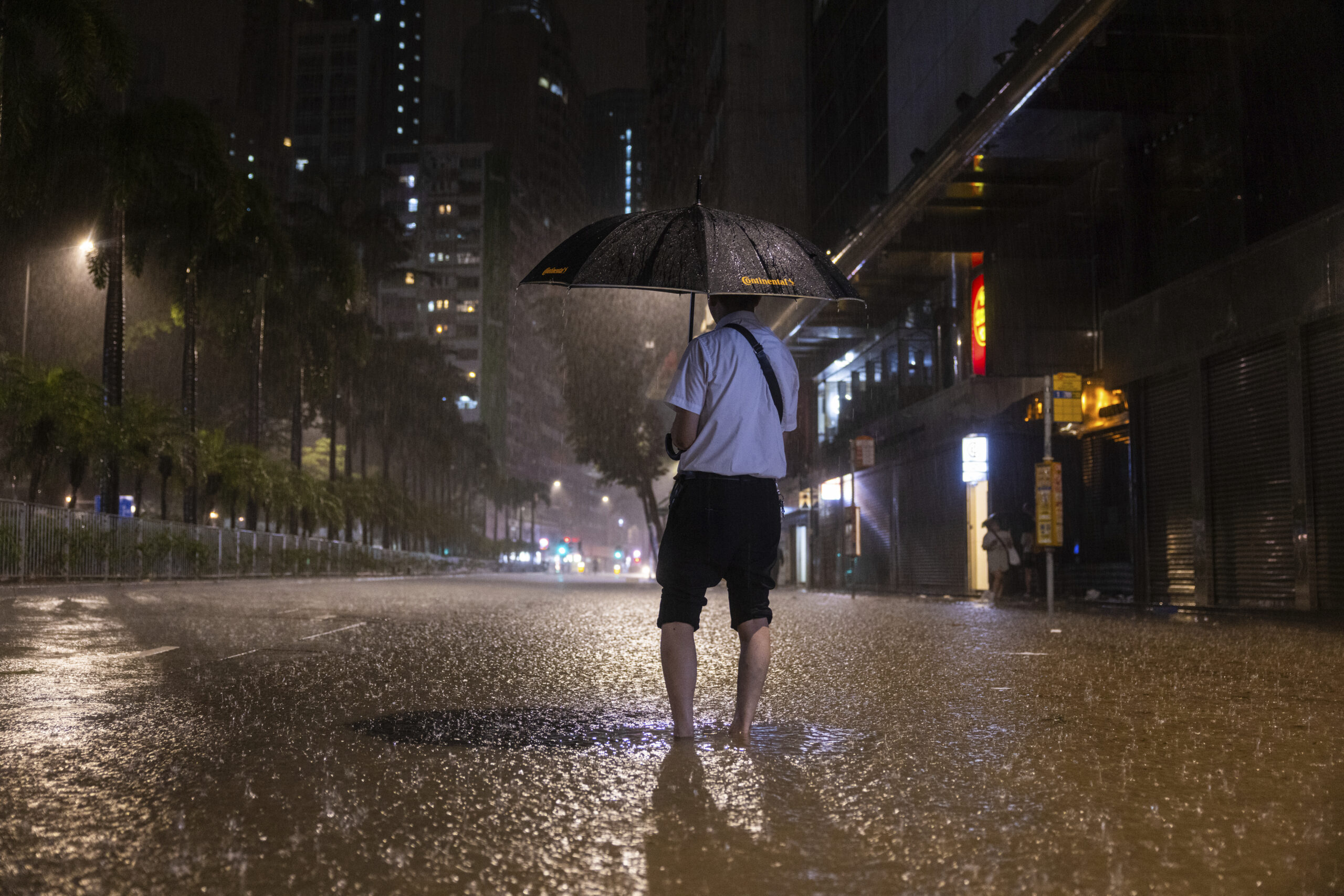 A pedestrian waits for a bus on a flooded street following heavy rainstorms. (AP Photo/Louise Delmo...