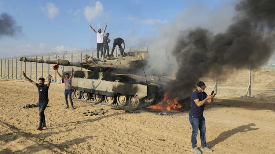Palestinians celebrate by a destroyed Israeli tank at the Gaza Strip fence east of Khan Younis Satu...