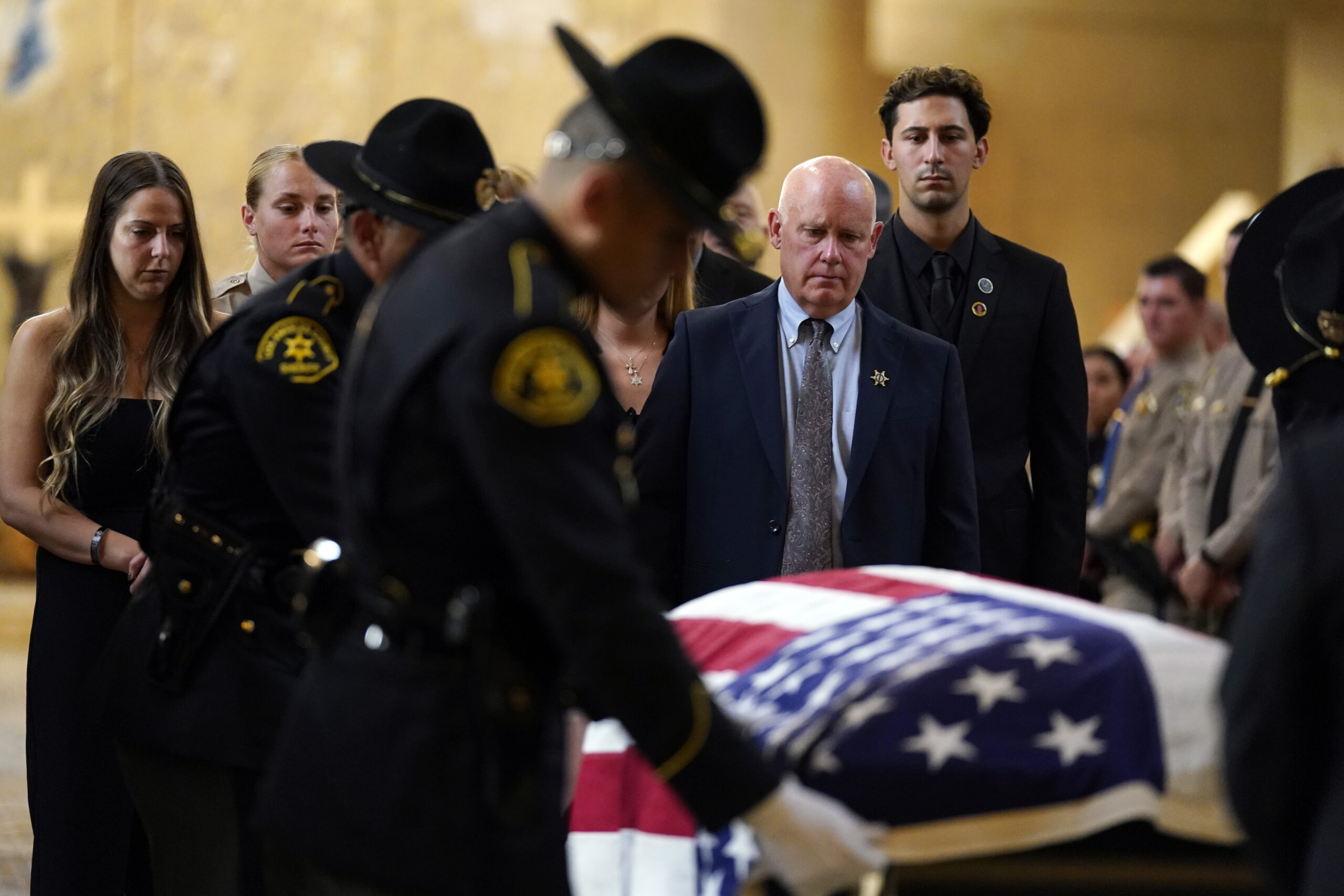 Mike Clinkunbroomer, center right, father of Los Angeles sheriff's deputy Ryan Clinkunbroomer watch...