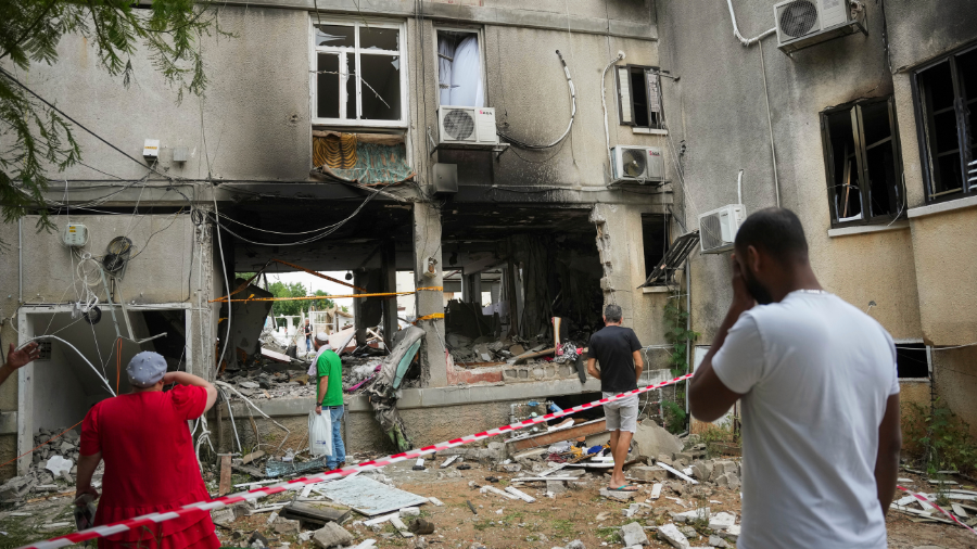 Image: Israelis inspect a damaged residential building after it was hit by a rocket fired from the ...