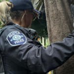 SPD officers and We Heart Seattle staff search through an encampment where human remains were uncovered. (Photo courtesy of We Heart Seattle)