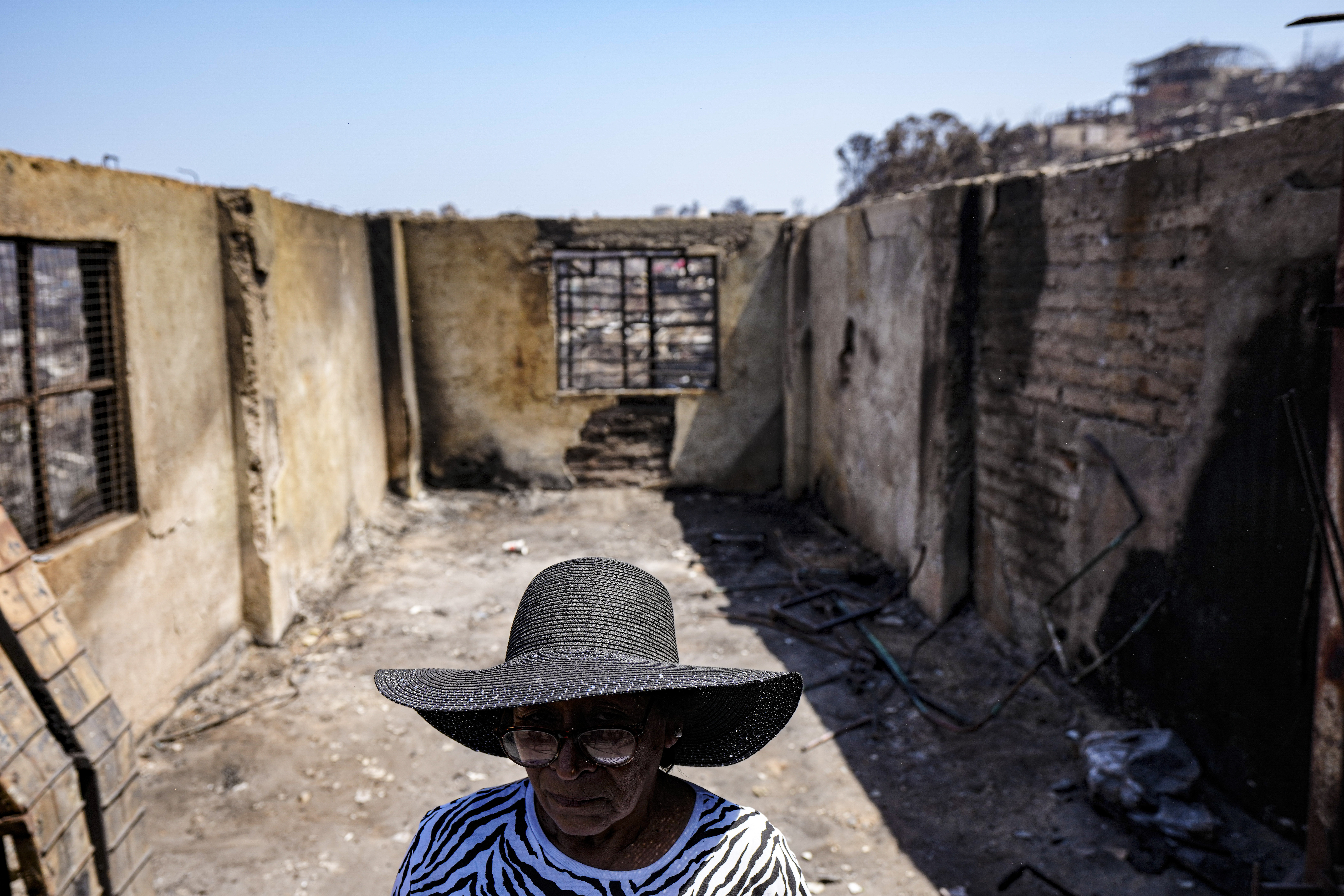 Aminta Guerra stands inside what is left of her charred home after a deadly forest fire affected th...