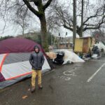 Image: A volunteer with We Heart Seattle is seen at a Seattle homeless encampment.