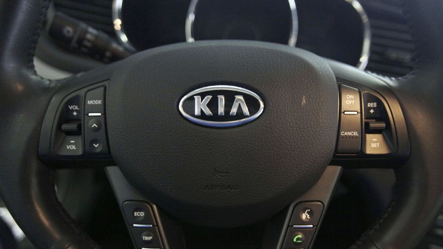 Photo: The Kia logo brands a steering wheel inside of a Kia car....