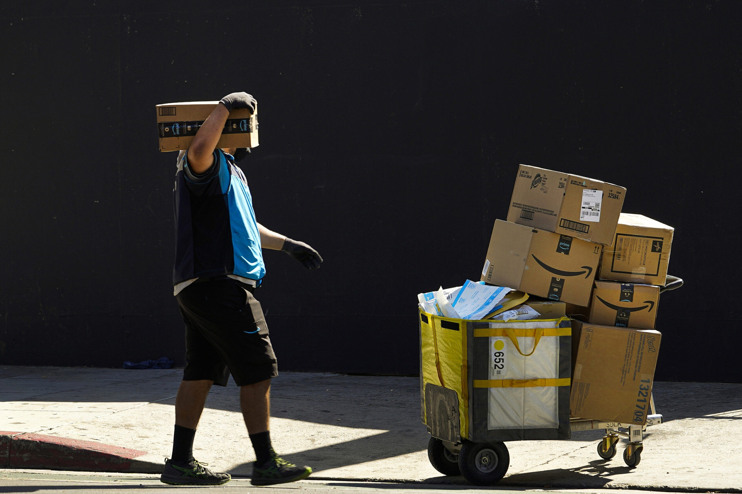 FILE - An Amazon worker delivers packages in Los Angeles on Oct. 1, 2020. July sales events have be...