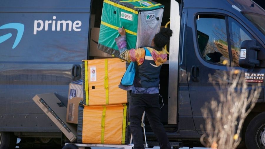 Photo: An Amazon Prime delivery person lifts packages while making a stop at a high-rise apartment ...