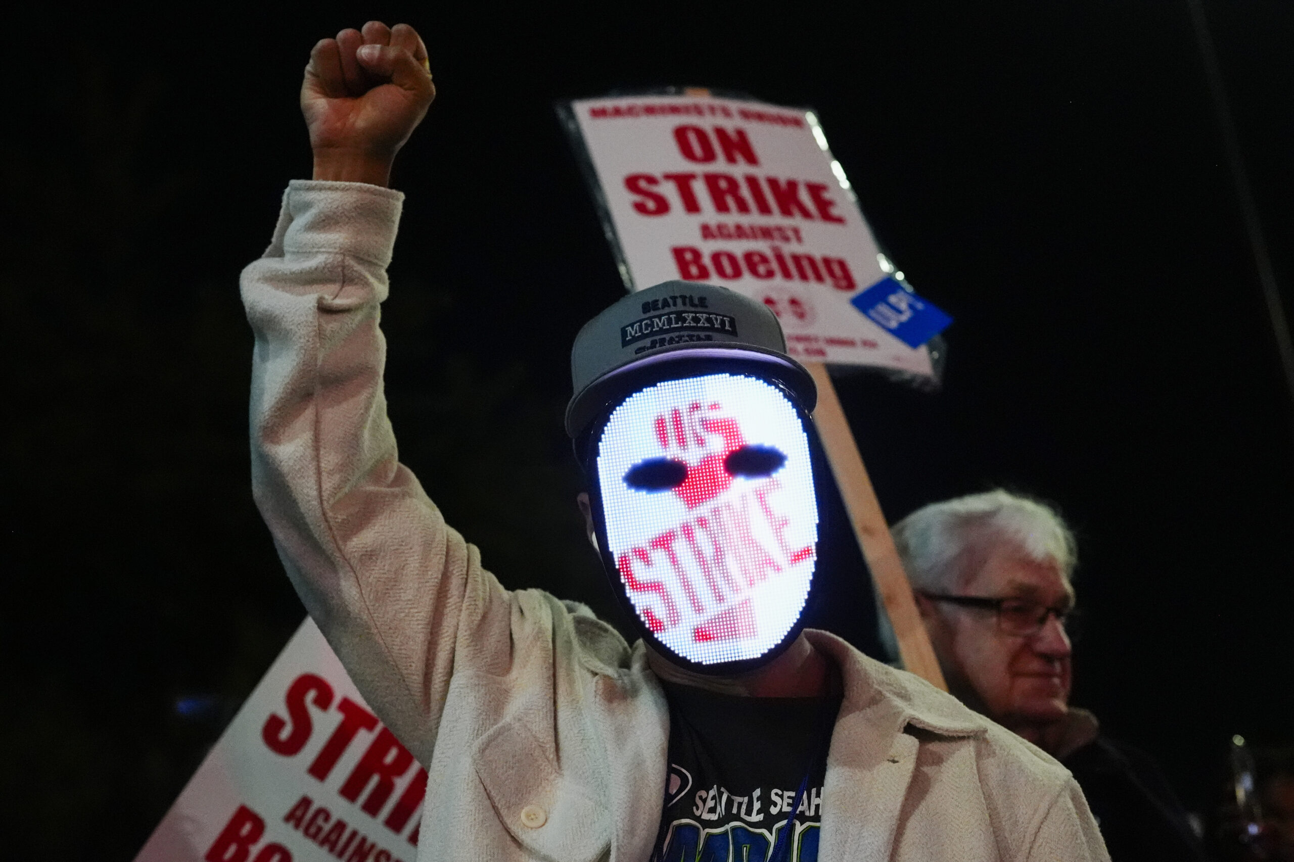 A Boeing worker wears a mask with a digital "strike" sign as employees picket after union members v...