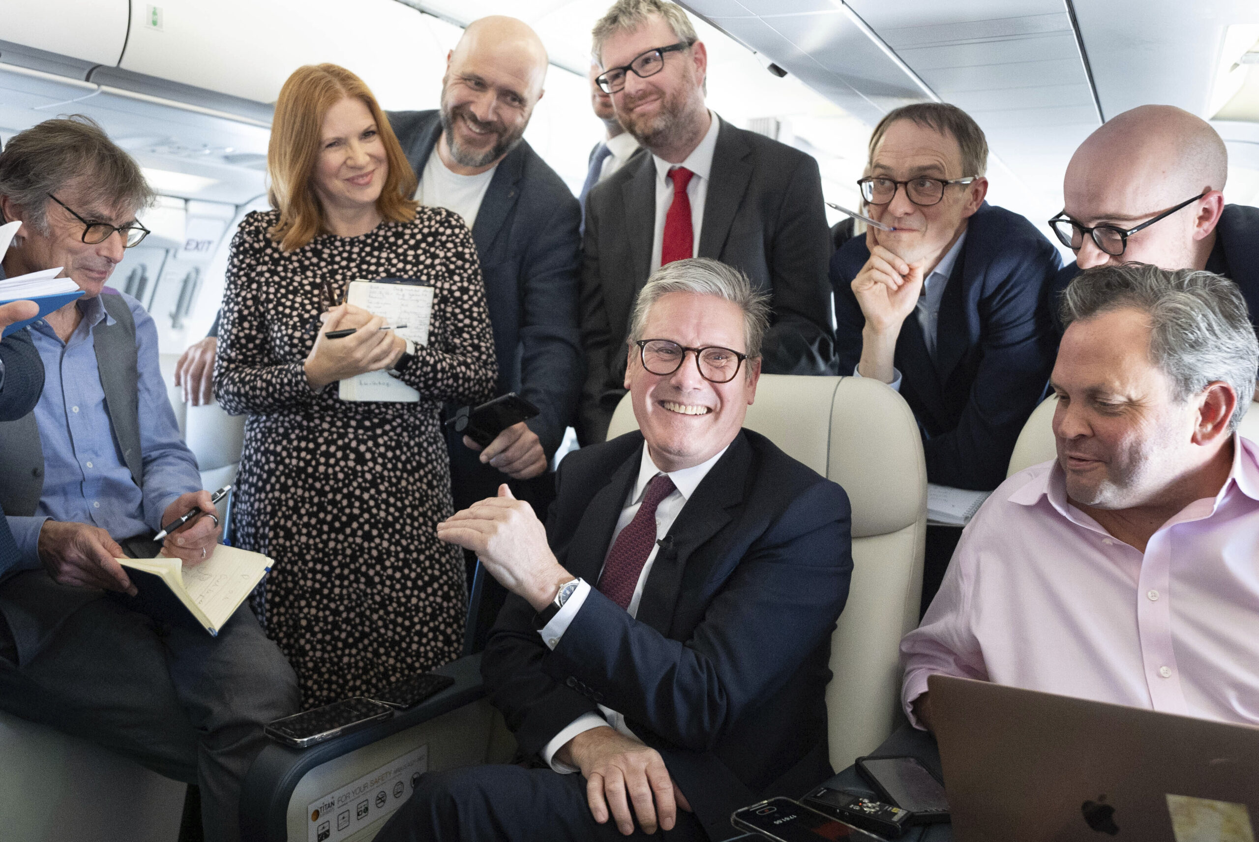 Britain's Prime Minister Keir Starmer, center, talks to the media on board his plane as he flies to...