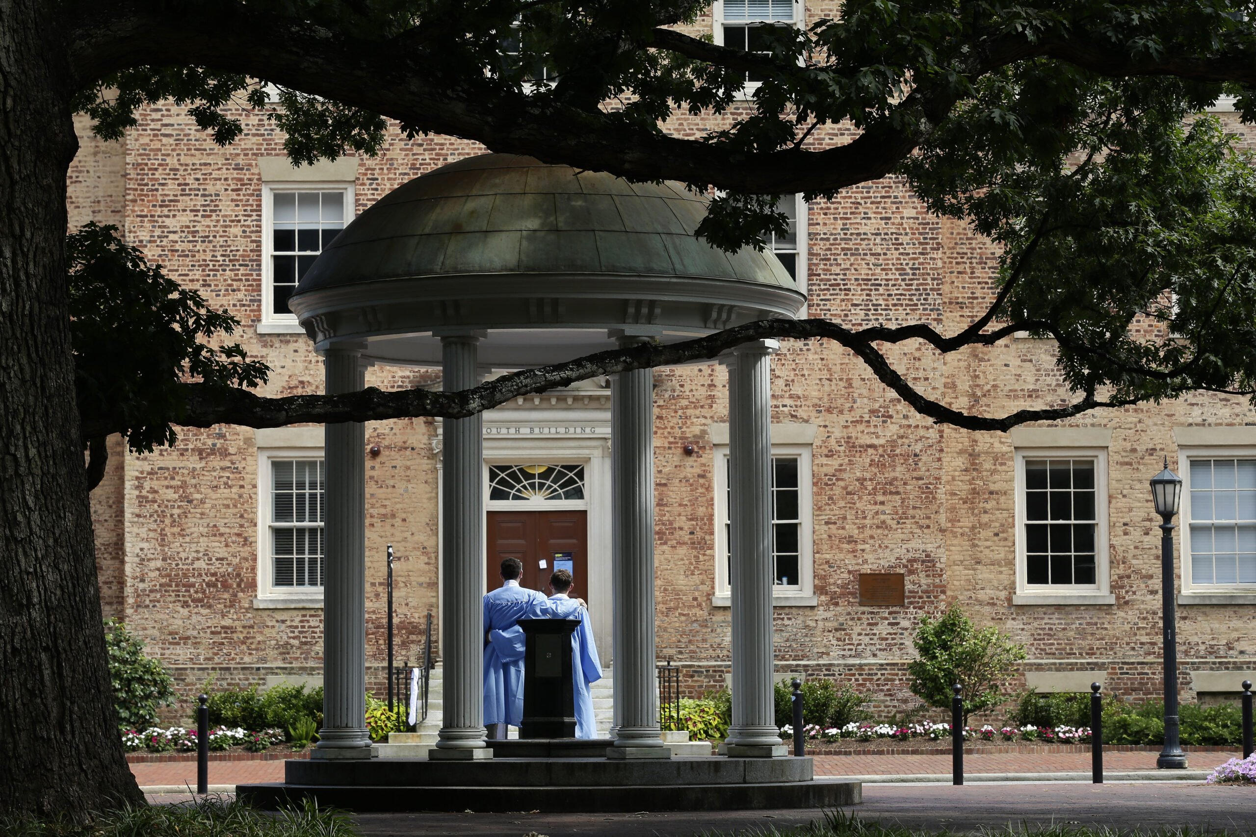 FILE - Graduates of the University of North Carolina take pictures at the Old Well on campus in Cha...