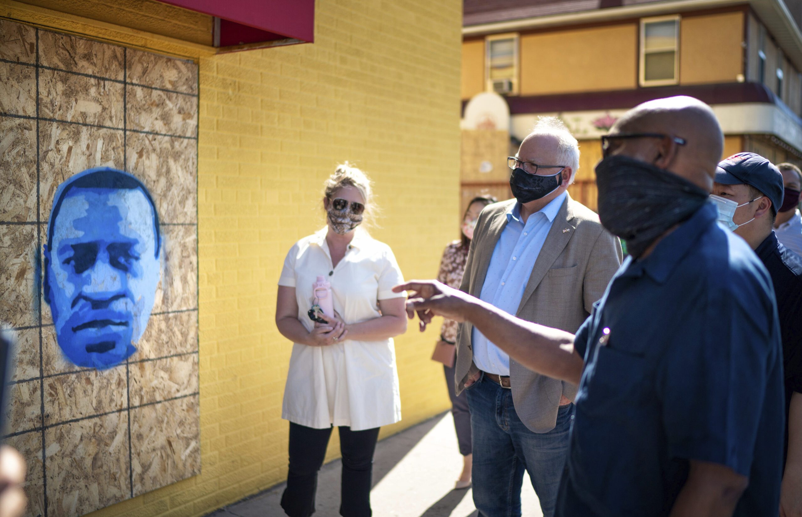 FILE - Minnesota Gov. Tim Walz, center right, listens to artist Seitu Jones, right, talk about his ...