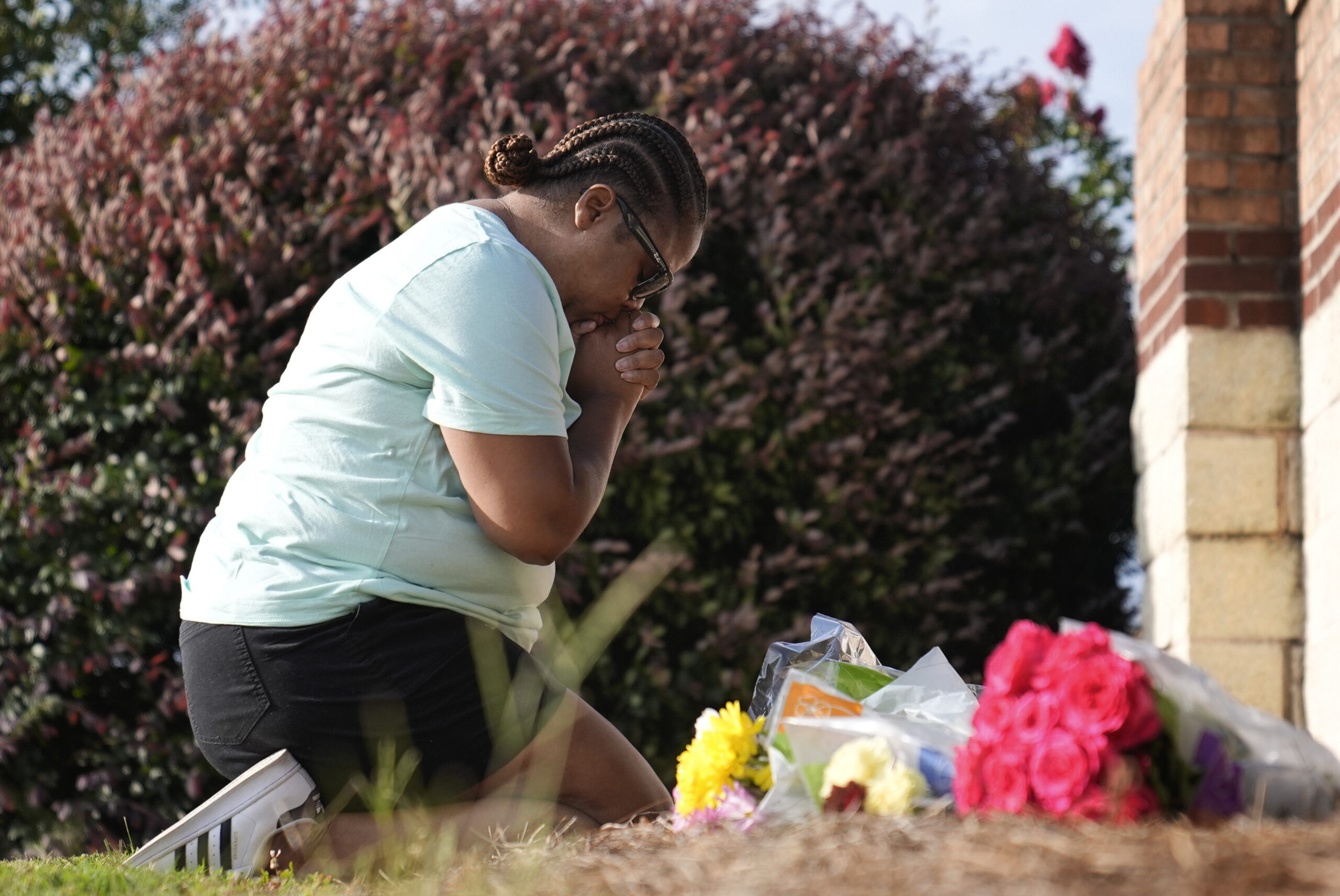 Linda Carter, of Grayson, Ga., kneels near Apalachee High School to place flowers as she mourns for...