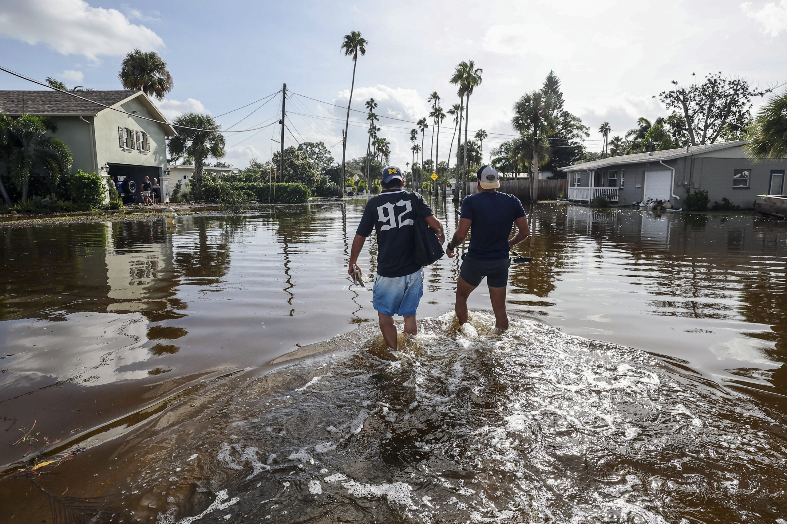 Thomas Chaves, left, and Vinny Almeida walk through floodwaters from Hurricane Helene in an attempt...