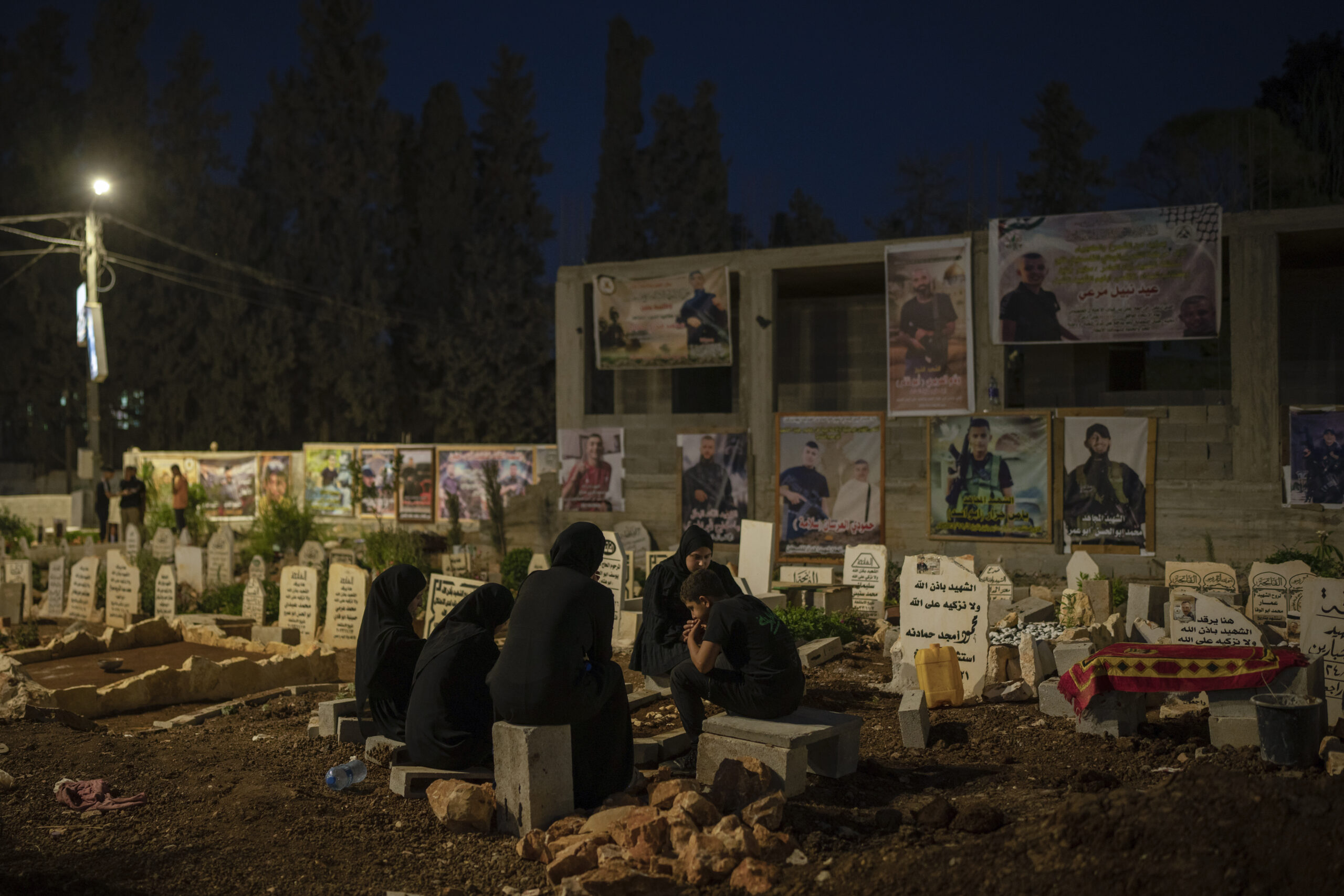 Family members sit next to the grave of Odei, 22, in Jenin, West Bank, Saturday, June 8, 2024. Odei...