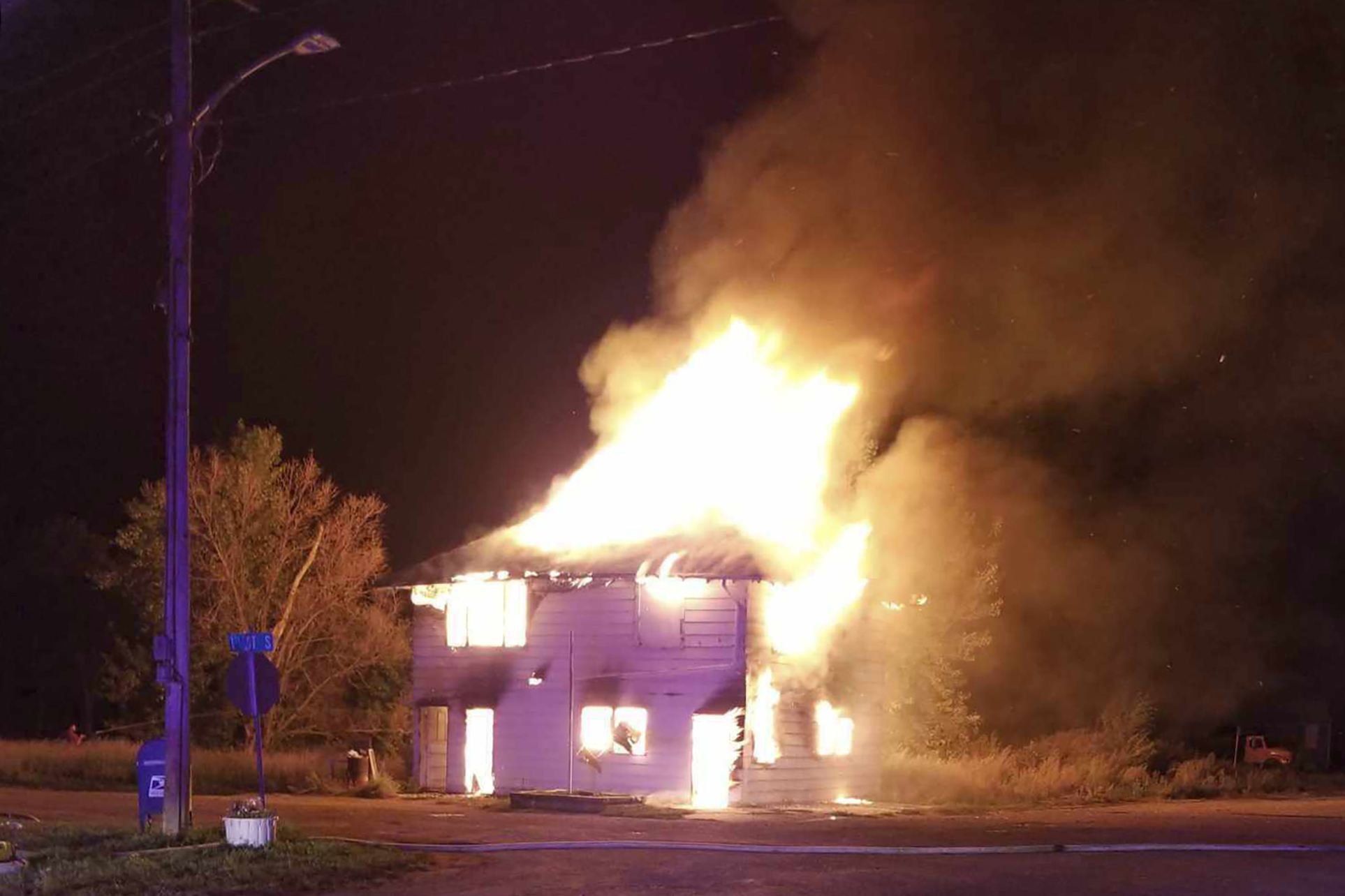 In this photo provided by Debbie Vollmuth, a fire consumes the post office in Selfridge, N.D., Mond...