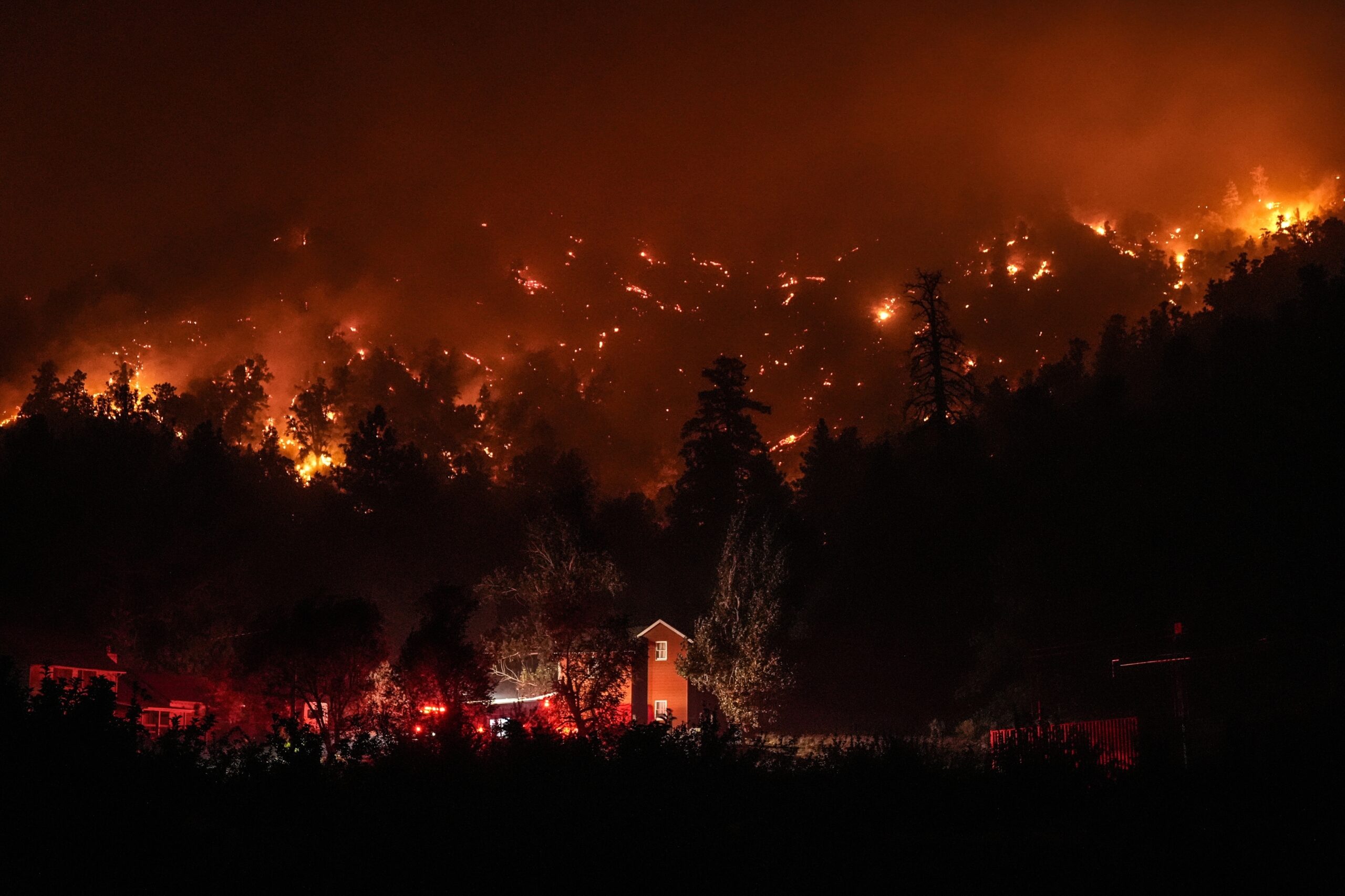 FILE - Firetrucks are seen around a building as scorched trees smolder during the Bridge Fire in Wr...