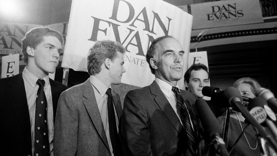 Image: U.S. Sen. Dan Evans stands in front of several microphones with his three sons, from left, M...