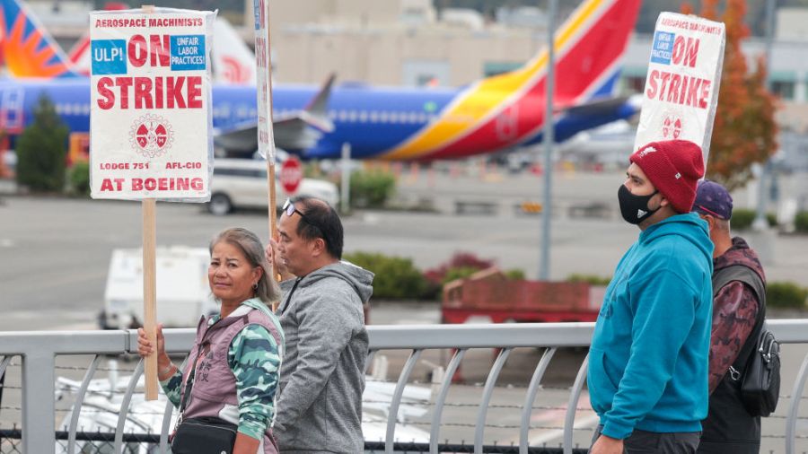 Photo: People carry Boeing-strike signs as they walk past parked Boeing 737 planes near Boeing Fiel...