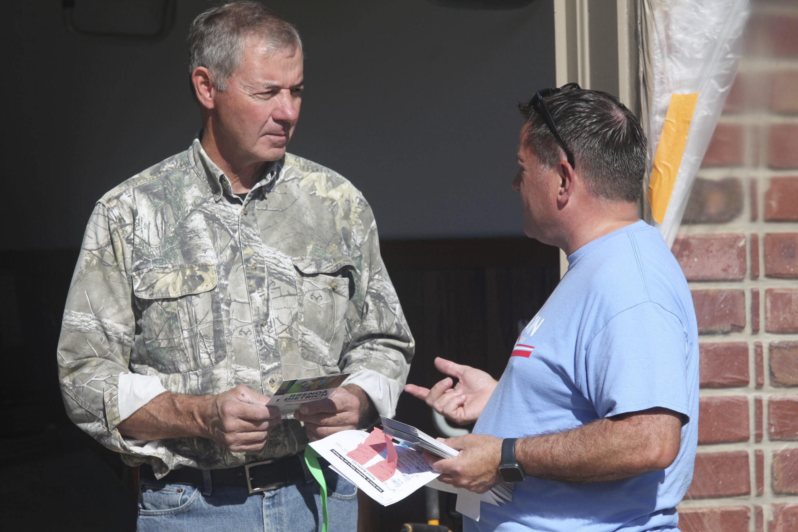 Bob Schmidt, right, a Republican voter, talks to state Rep. Jesse Borjon, left, R-Topeka, outside t...