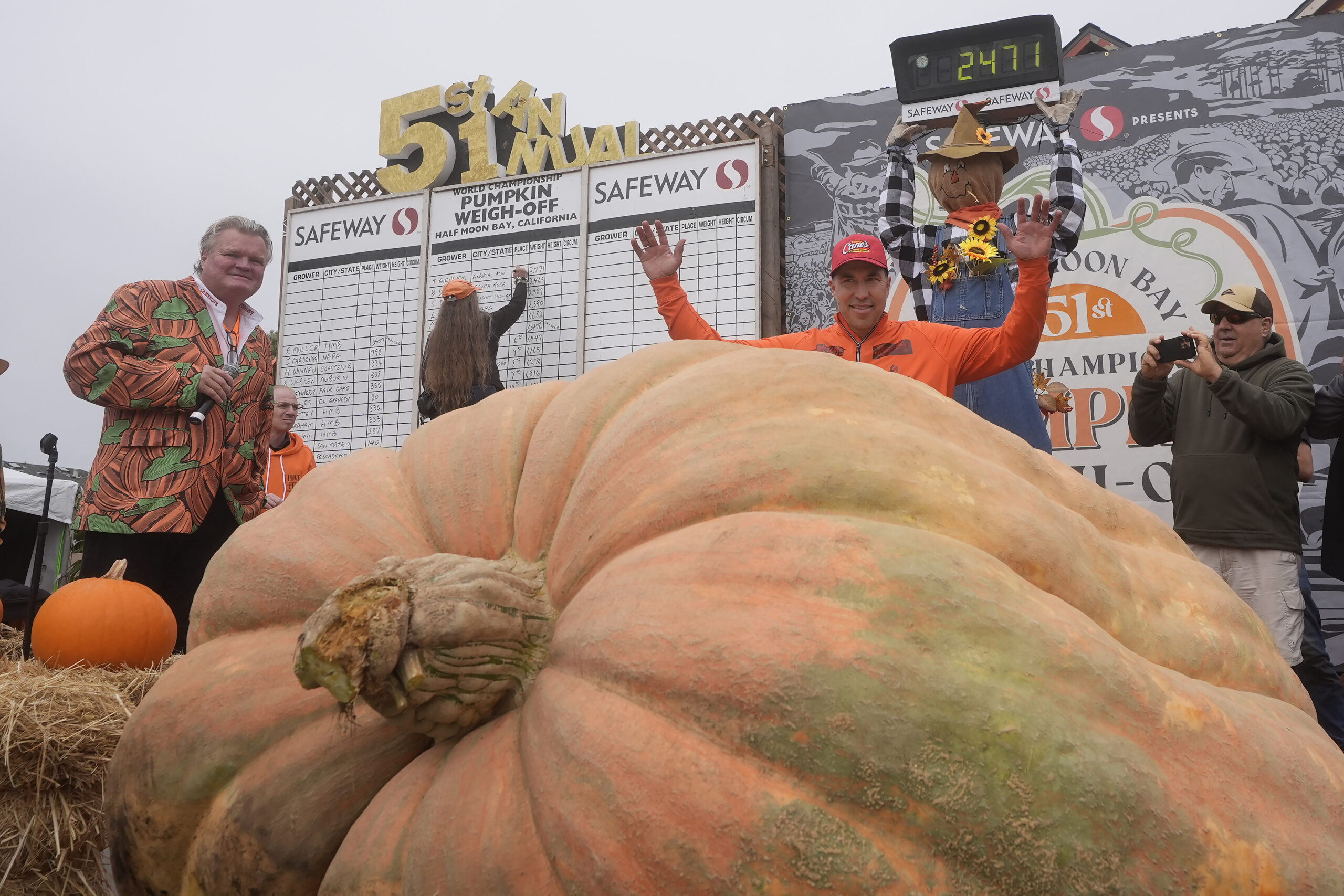 Travis Gienger, of Anoka, Minn., middle, celebrates after his pumpkin weighed in at 2,471 pounds to...