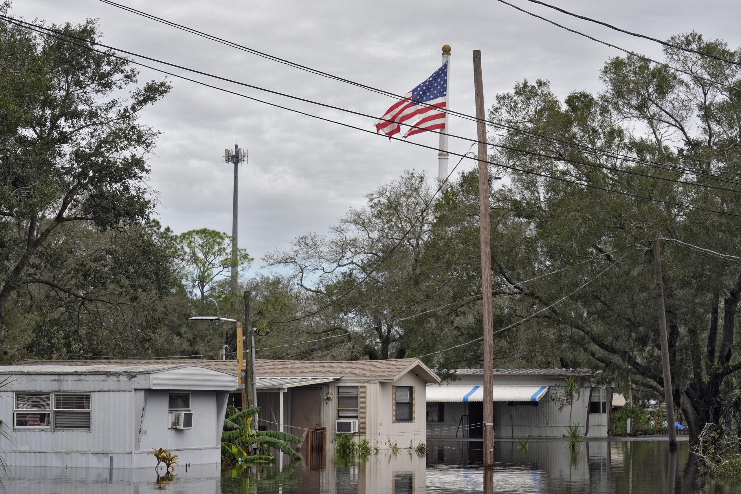 A tattered American flag flies above flooded homes, from Hurricane Milton along the Alafia river Fr...