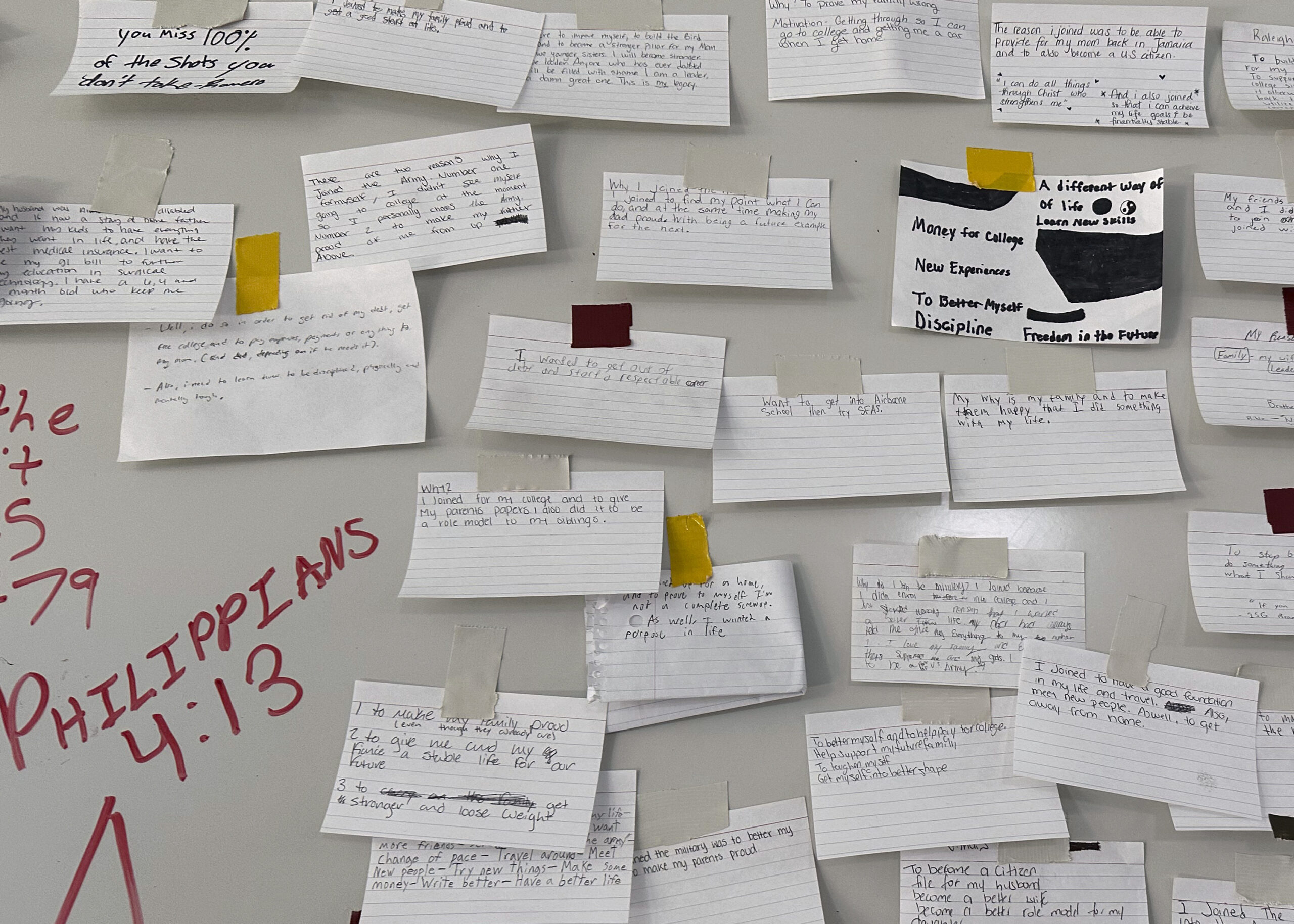 Index cards describing why the recruits joined the Army are taped to a large board on a wall at For...