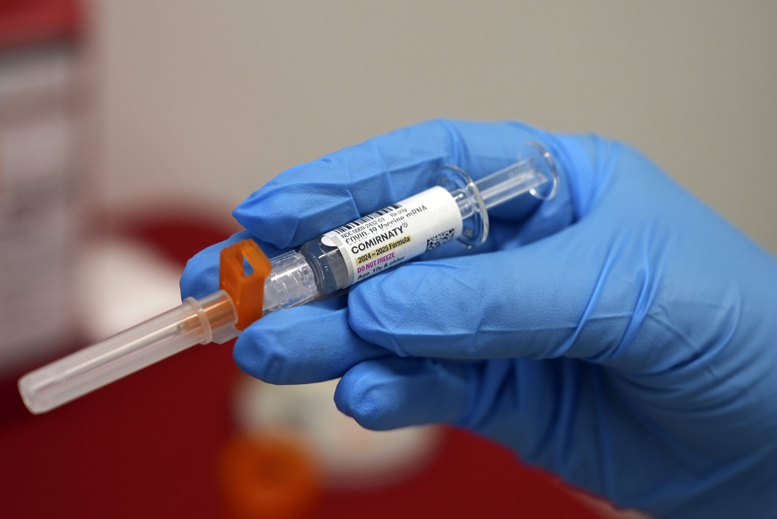 FILE - A pharmacist holds a COVID-19 vaccine at a pharmacy in New York, on Sept. 24, 2024. (AP Phot...