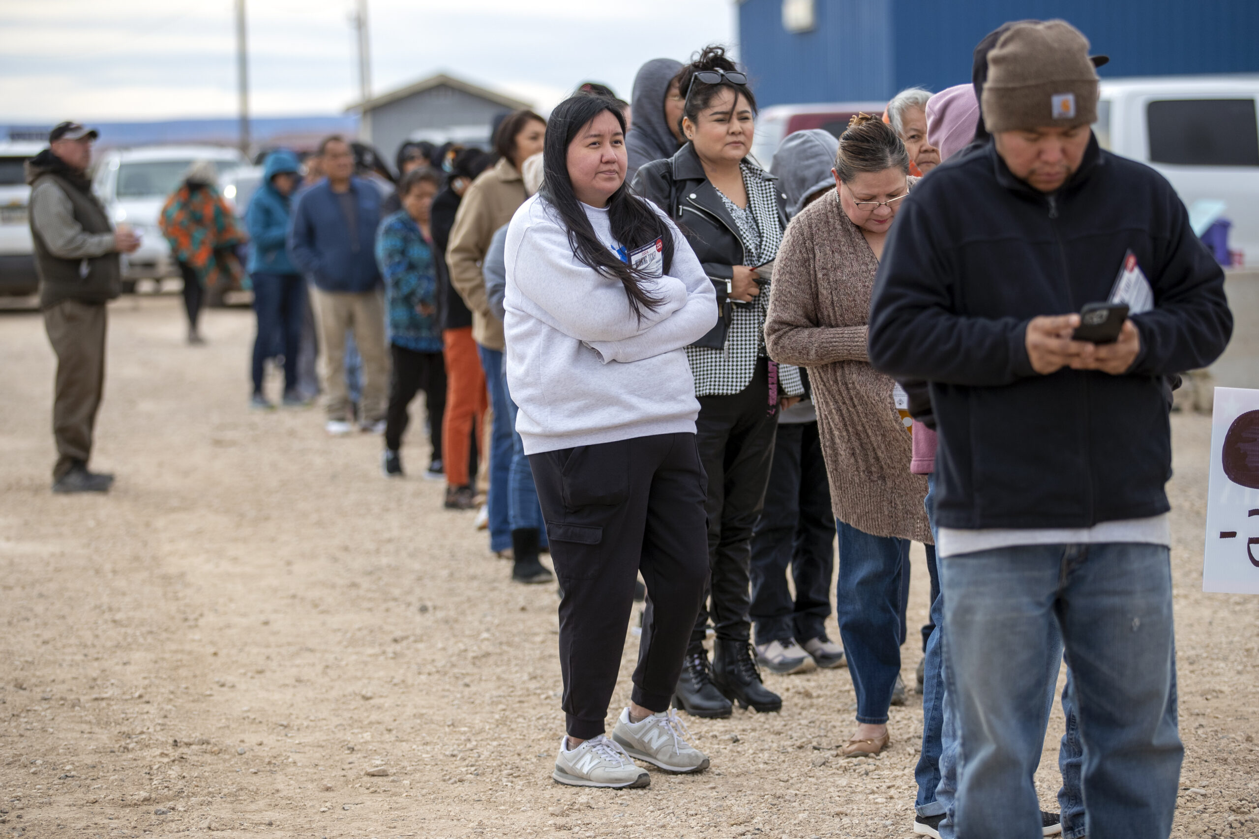 Voters wait in line to cast their ballots outside a polling station on the Navajo Nation in Chinle,...