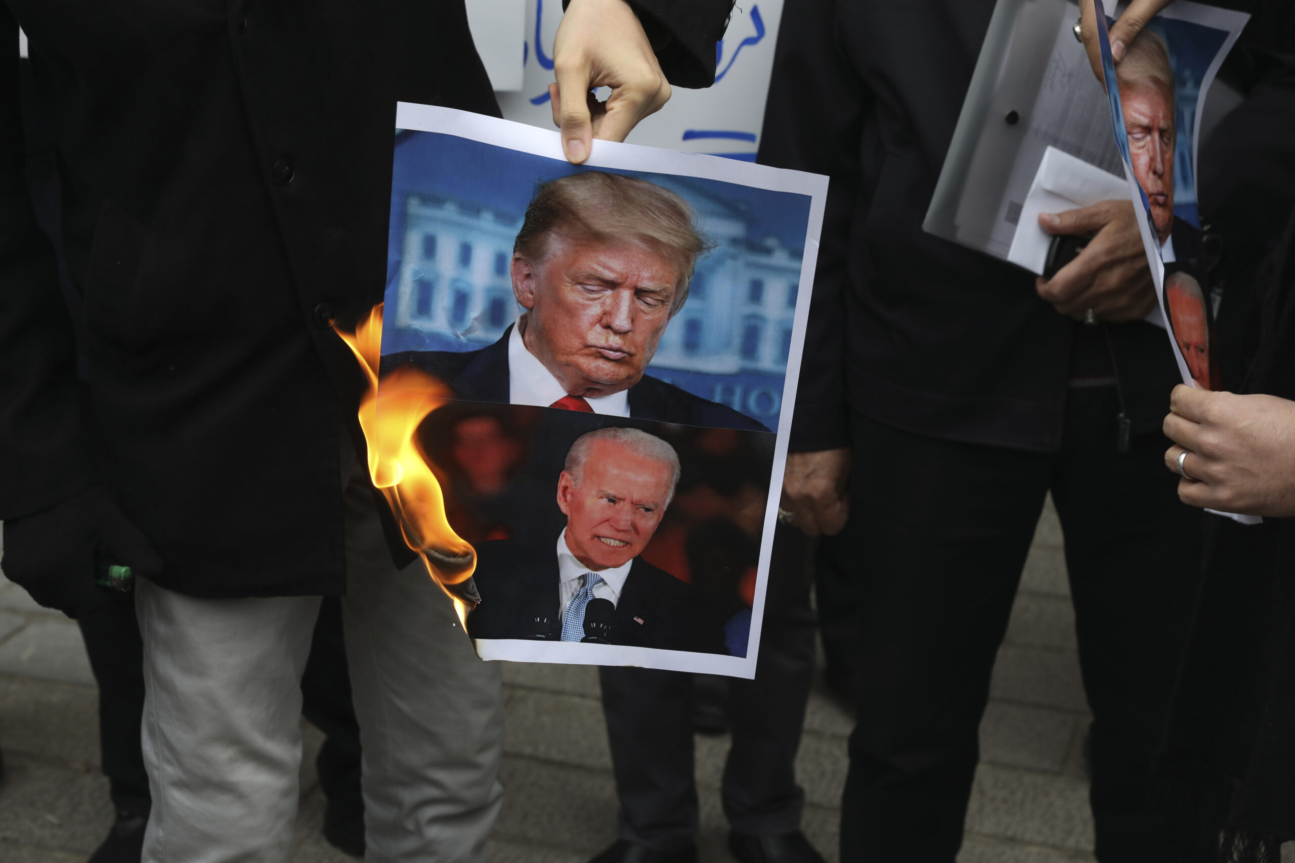 FILE — A group of protesters burn pictures of then-U.S. President Donald Trump, top, and then-Pre...