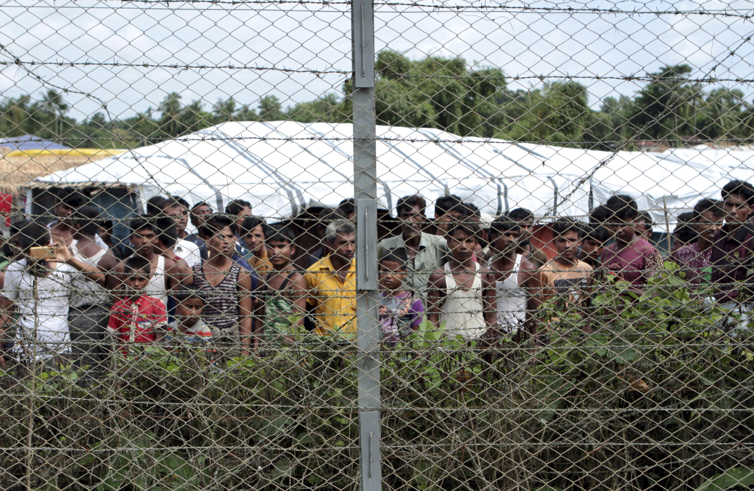 FILE - Rohingya refugees gather near a fence during a government organized media tour, to a no-man'...