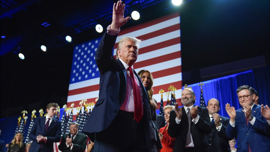 Image: President-elect Donald Trump waves as he walks with former first lady Melania Trump at an el...