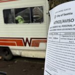A sign from the city of Seattle ordering the removal of private property from the city's street can be seen in January 2025 while an RV can be seen in the background. (Photo: Charlie Harger, KIRO Newsradio)