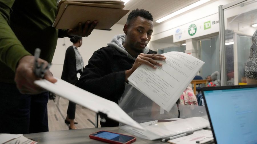 Photo: Petterly Jean-Baptiste, center, an immigrant from Haiti, registers Nov. 16, 2023, with the I...