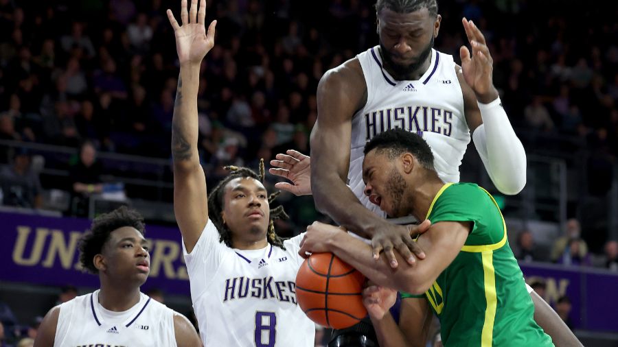 Franck Kepnang #11 of the Washington Huskies fouls Kwame Evans Jr. #10 of the Oregon Ducks during t...